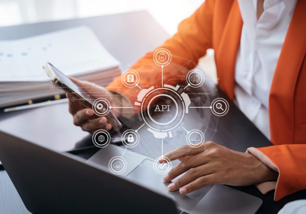 Person using laptop and smartphone with API.